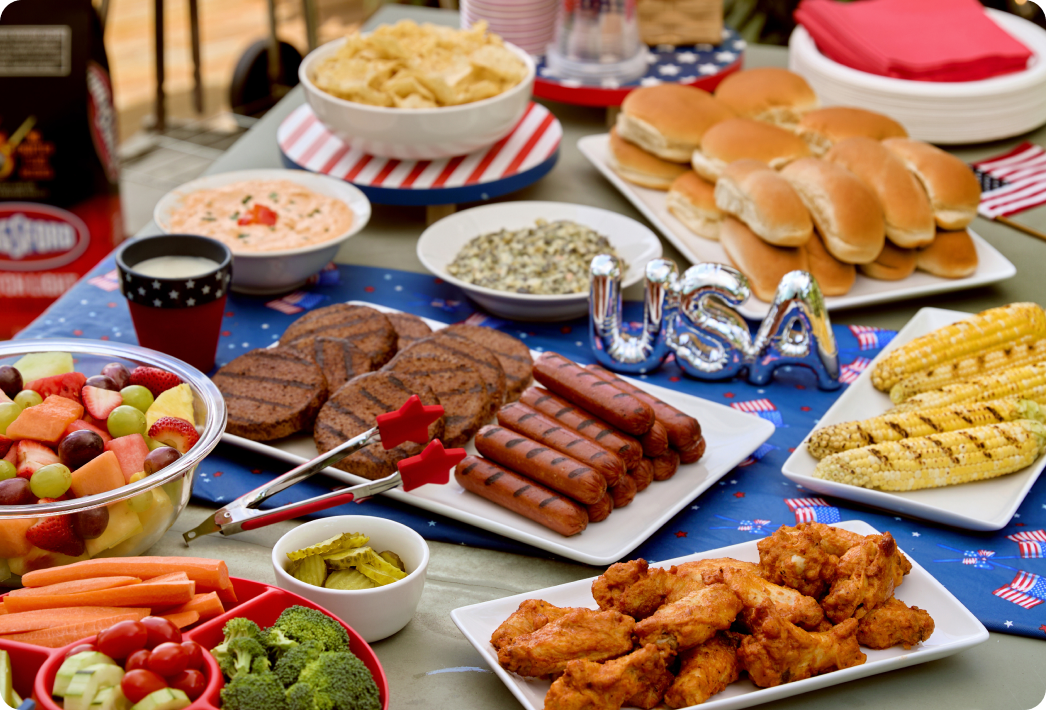 Summer cookout spread with grilled foods, sides, and patriotic table setup