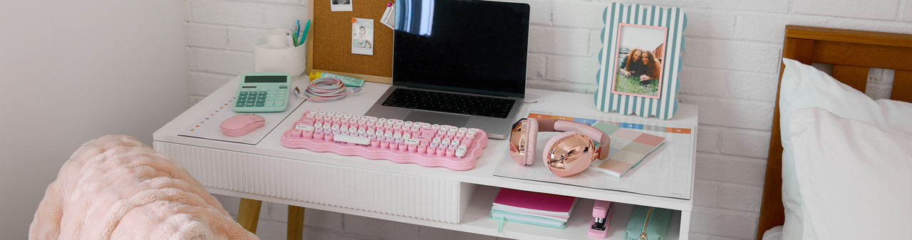 Study desk with pastel desk accessories: pink keyboard and mouse, mint calculator, journals, headphones & more from pOpshelf.
