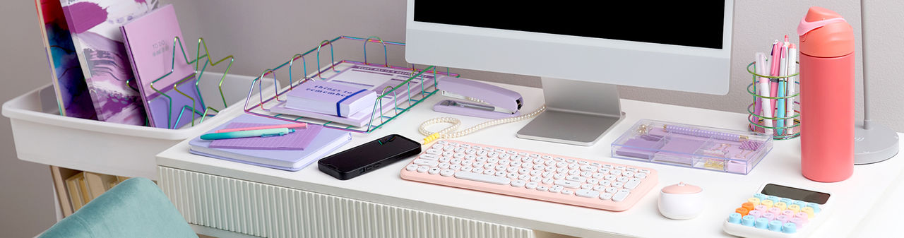 Study desk with pastel desk accessories: pink keyboard and mouse, colorful calculator, wire desk organizers, markers, pens & more.. 