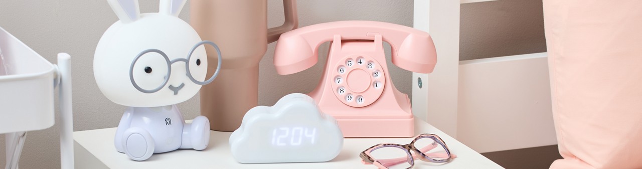 Back-to-school electronics: vintage pink telephone headset, bunny lamp, and whilte cloud-shaped digital clock.