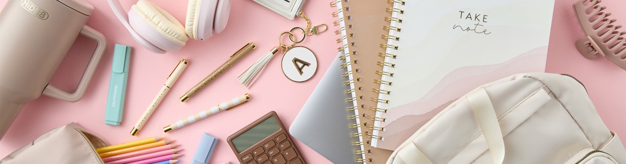 Neutral-toned back-to-school supplies: cream backpack, white headphones, spiral notebooks, tan pouch with colored pencils pastel highlighters, pens & more.