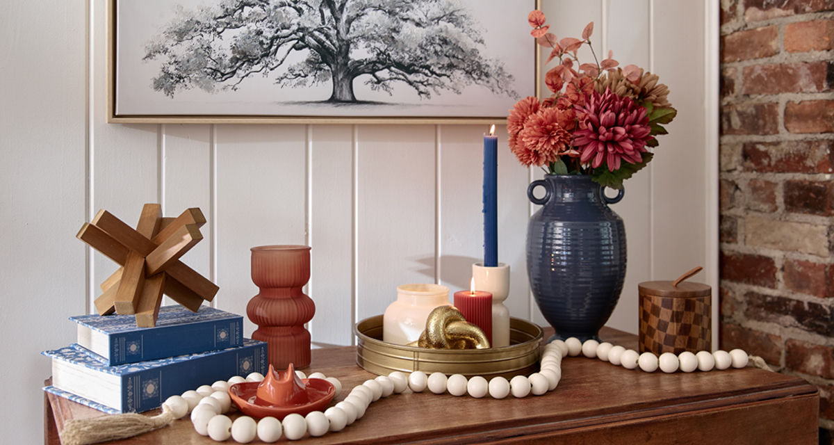 Console table decorated with decor from the Canyon Bues collection at pOpshelf: glass vase, wooden acccents, large blue vase with fall floral, white wooden bead garland, candes & more.