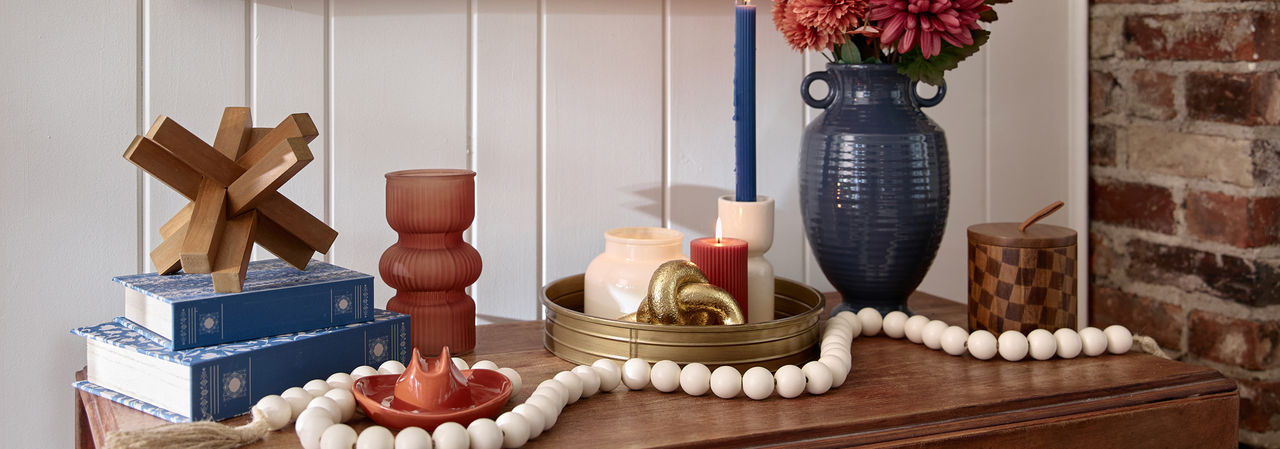 Console table decorated with decor from the Canyon Bues collection at pOpshelf: glass vase, wooden acccents, large blue vase with fall floral, white wooden bead garland, candes & more.