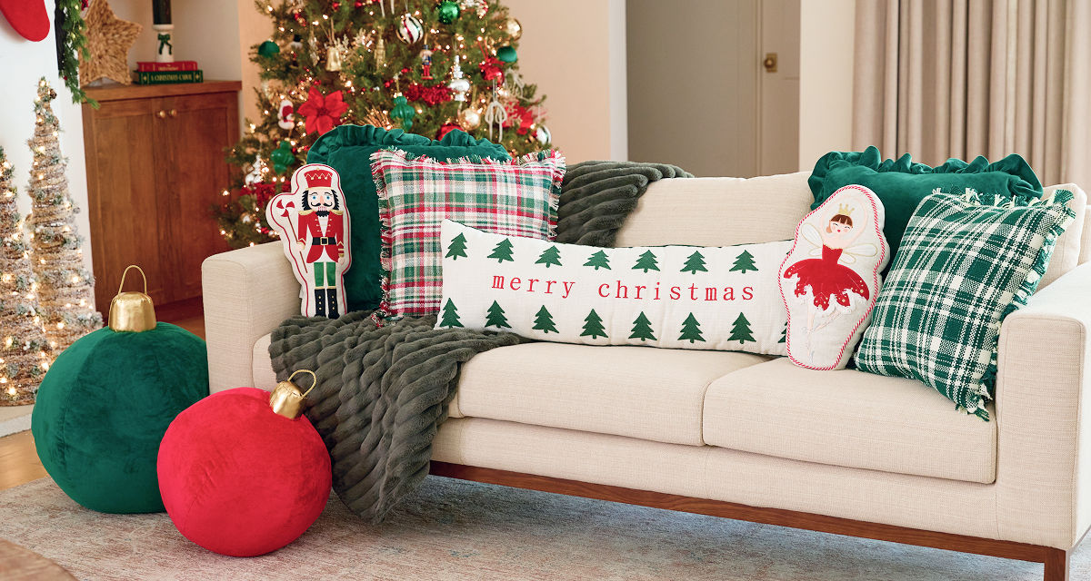 Christmas pillows in various shapes and designs on a sofa: red and greed jumbo ornament pillows, velvety green and plaid pillows, lumbar pillow, and more.