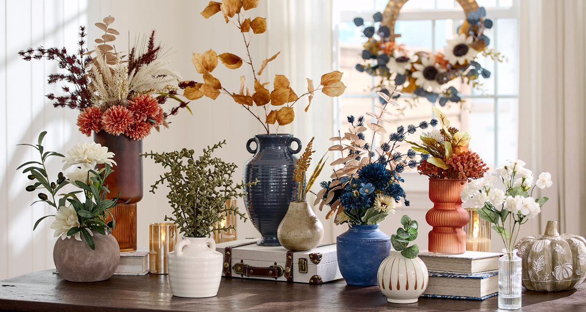 Fall floral bushes, fall branches, and floral picks in vases and premade fall floral arrangements on an entryway table.