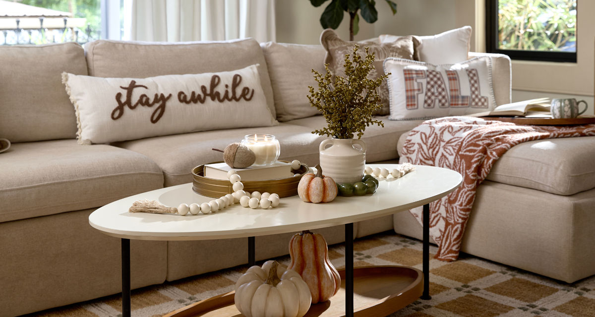 Living room decorated for fall with fall pillows and throws, pumpkin and fall decor, fall candles, and fall floral.