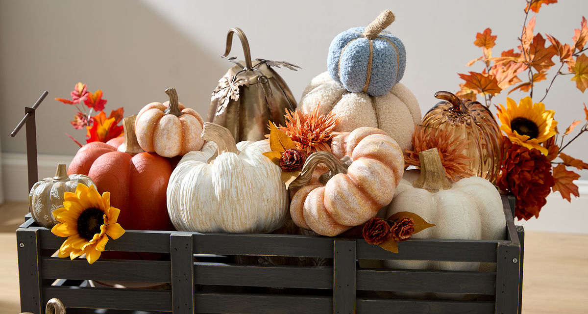 Pumpkins from pOpshelf in various sizes, textures, and colors in a wagon on a porch.