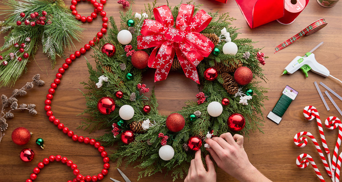 Christmas craft supplies: wooden handheld DIY masks, DIY snowflake porch leaner, green, red, and plaid wired ribbon, DIY plastic fillable ornaments & more.