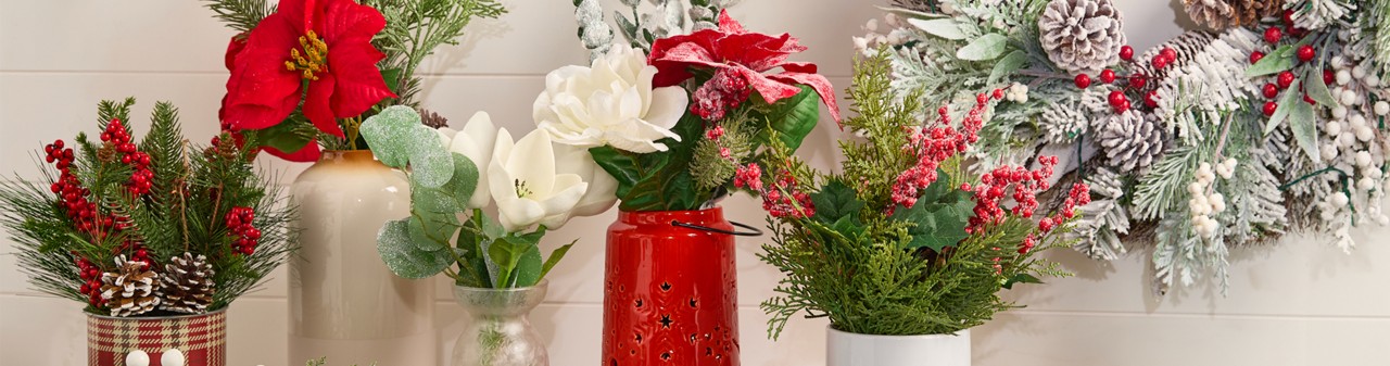 Four vases filled with faux Christmas florals and greenery: red & white poinsettias, frosted & flocked pine and pinecones, Christmas wreath, holly and berries, and more.