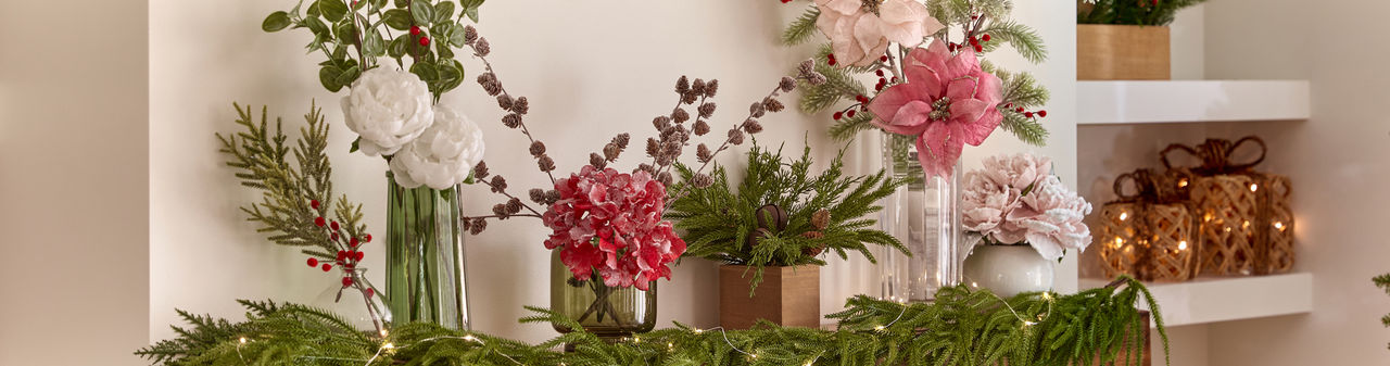 Vases filled with faux Christmas florals and greenery: red, pink & white poinsettias, frosted & flocked pine and pinecones, Christmas wreath, holly and berries, and more.