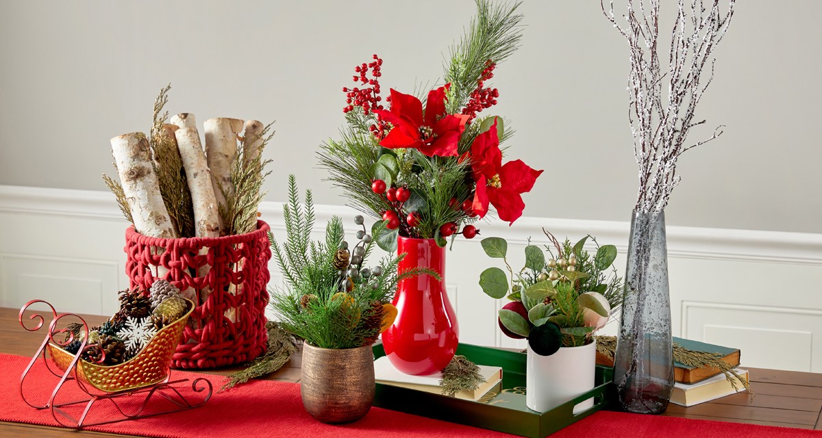 Christmas Sleigh with decorative pinecones, red woven basket with faux birch logs, and  4 glass vases filled with faux Christmas florals and greenery.