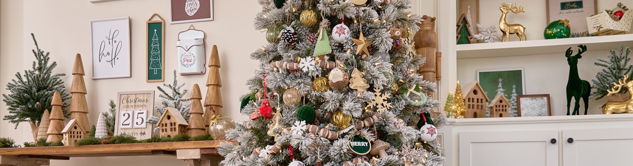 Room with Christmas tree decorated for Christmas in the Winter Woodlands colletion with large solid-wood trees and nutcrackers, wooden garland, wooden village houses, and rustic and deer accents.