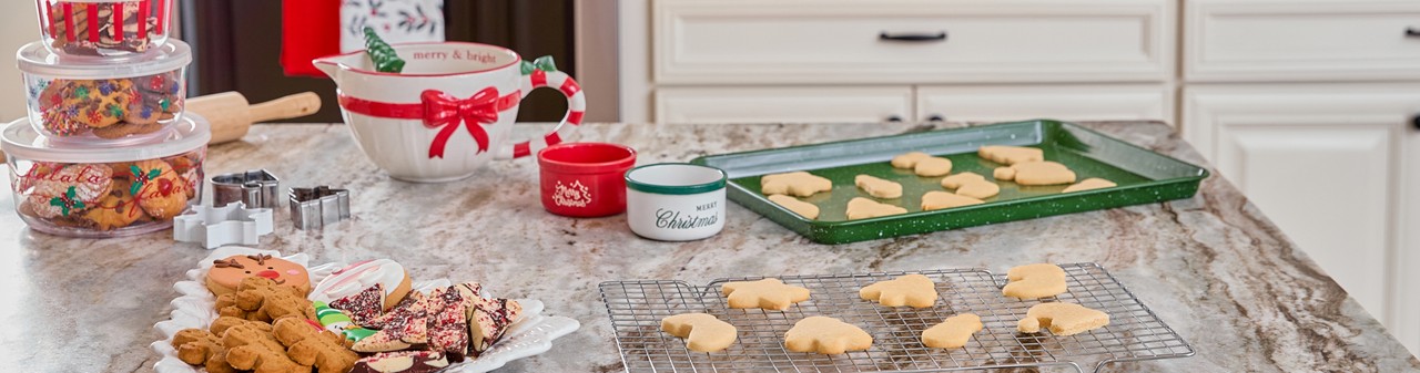 Christmas mixing bowl, cookie sheets, cookie cutter, tree-shaped ceramic platter, plastic food storage and more in a kitchen decorated for Christmas.