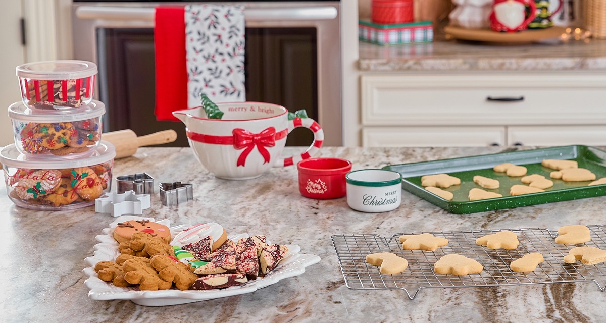 Christmas mixing bowl, cookie sheets, cookie cutter, tree-shaped ceramic platter, plastic food storage and more in a kitchen decorated for Christmas.