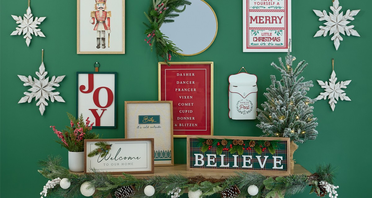 Christmas signs and wall decor in various sizes and designs on a green wall.