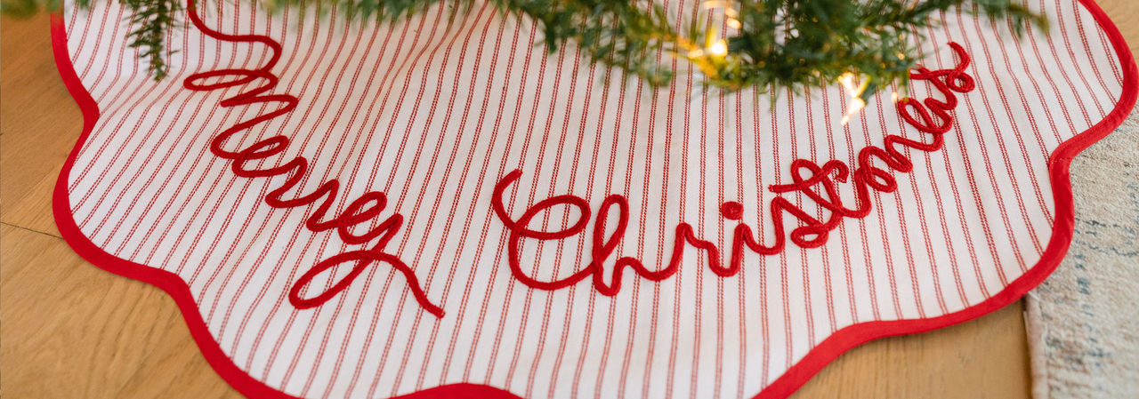 Red & white striped "Merry Christmas" tree skirt around a decorated Christmas tree.