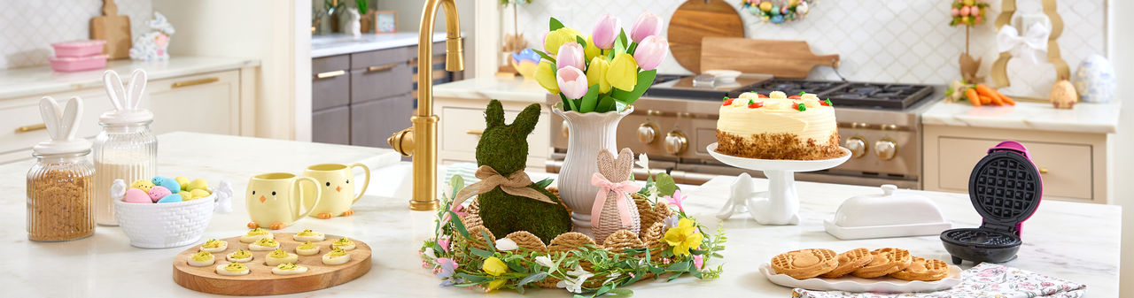 Easter kitchen with wooden egg serving board, bunny canisters, bunny charcuterie board, bunny waffle maker, and Easter decor.
