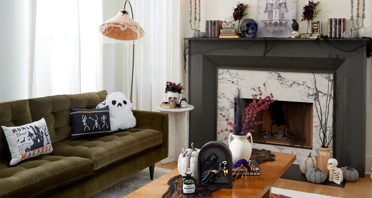 Living room and mantel with spooky Halloween decorations: black metal jack-o-lanterns, ghost and skeleton pillows, skulls, crows, poison bottles, spellbooks & more.