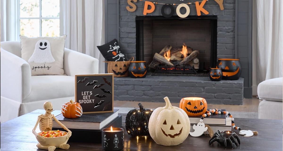 Living room and fireplace with Halloween decorations: black metal, ceramic & wicker basket jack-o-lanterns, ghost and skeleton pillows, skeleton bowl, spider candleholder & more..