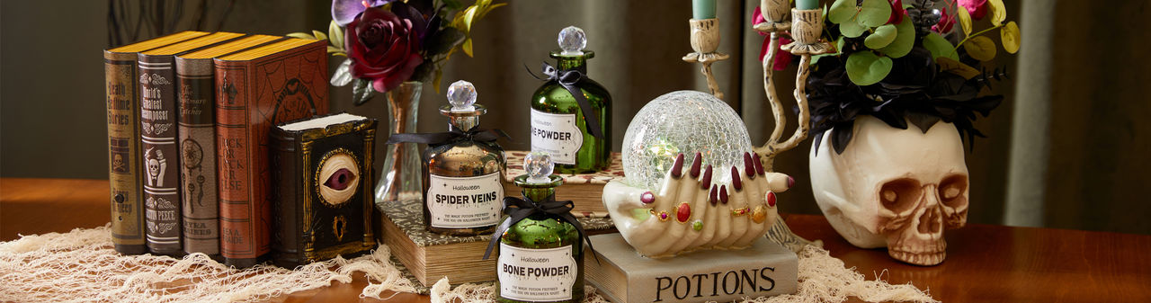 Spooky Halloween tabletop decor from pOpshelf: spell books, skull with crow, skull candlesticks and spooky candelabra, and poison bottles.