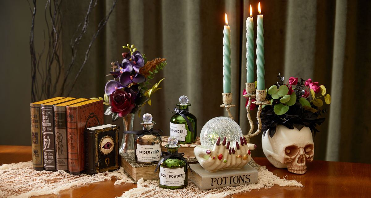 Spooky Halloween tabletop decor from pOpshelf: spell books, skull with crow, skull candlesticks and spooky candelabra, and poison bottles.