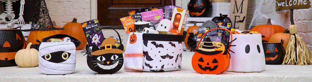 Halloween trick-or-treat buckets and bags filled with candy and goodies on a front porch decorated for Halloween. 