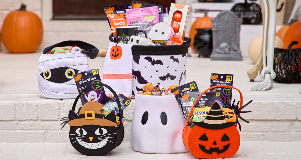 Halloween trick-or-treat buckets and bags filled with candy and goodies on a front porch decorated for Halloween. 