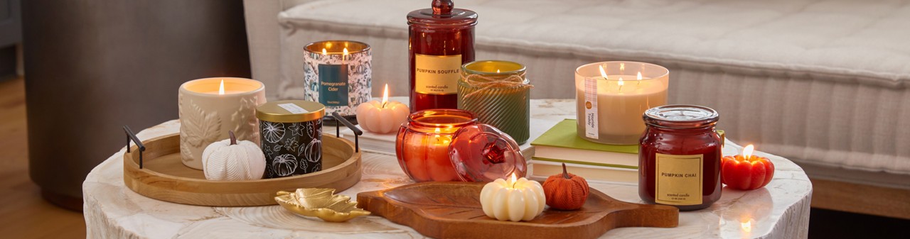 Various fall jar candles and pumpkin-shaped candles in fall scents.