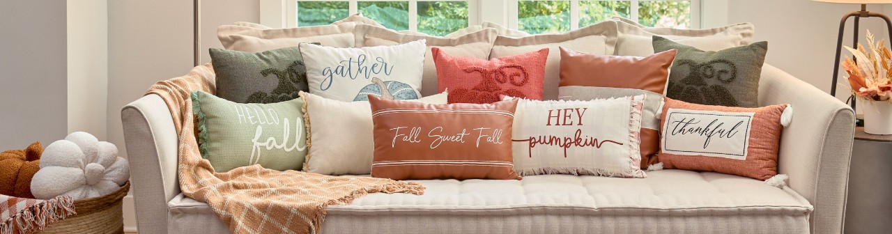 Fall pillows in various colors and designs on a living room sofa.