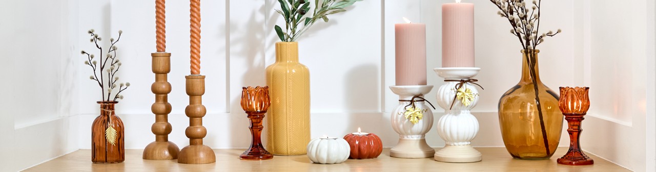 Fall vases and candleholders in various designs and colors on an entryway table.