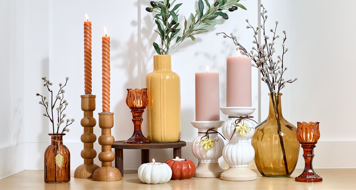 Fall vases and candleholders in various designs and colors on an entryway table.