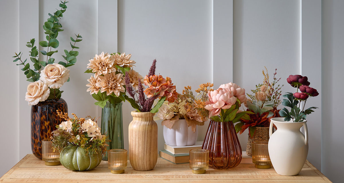Fall floral bushes, fall branches, and floral picks in vases and premade fall floral arrangements on an entryway table.
