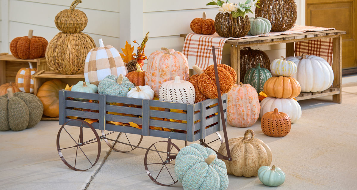 Pumpkins from pOpshelf in various sizes, textures, and colors in a wagon on a porch.