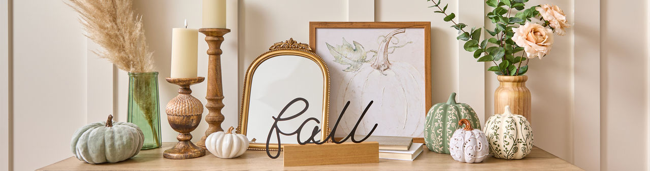 Fall tabletop decor on entryway table: pumpkins, flowers in vases, wooden candlestick holders, wooden vase, gold mirror and more.