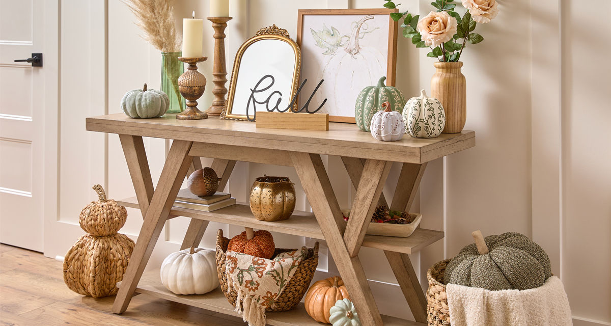 Fall tabletop decor on entryway table: pumpkins, flowers in vases, wooden candlestick holders, wooden vase, gold mirror and more.