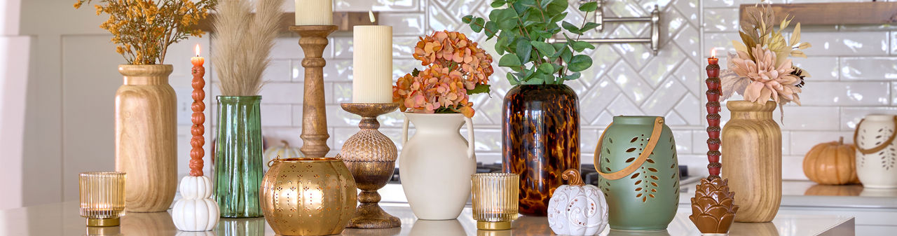 Fall vases and candleholders in various designs and colors in a kitchen.
