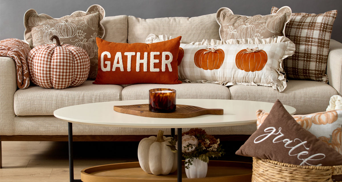 Fall pillows and throws in various colors and designs on a sofa.