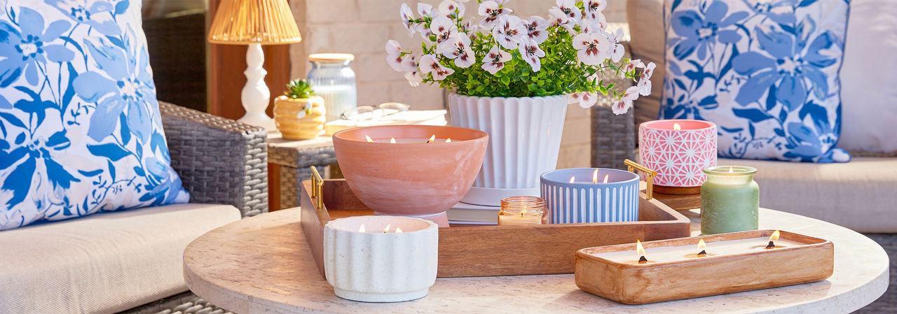 Citronella candles from pOpshelf in various sizes and designs on a wooden table.