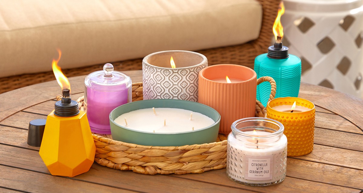 Citronella candles and torches from pOpshelf in various sizes, designs, and colors on a wooden porch table.