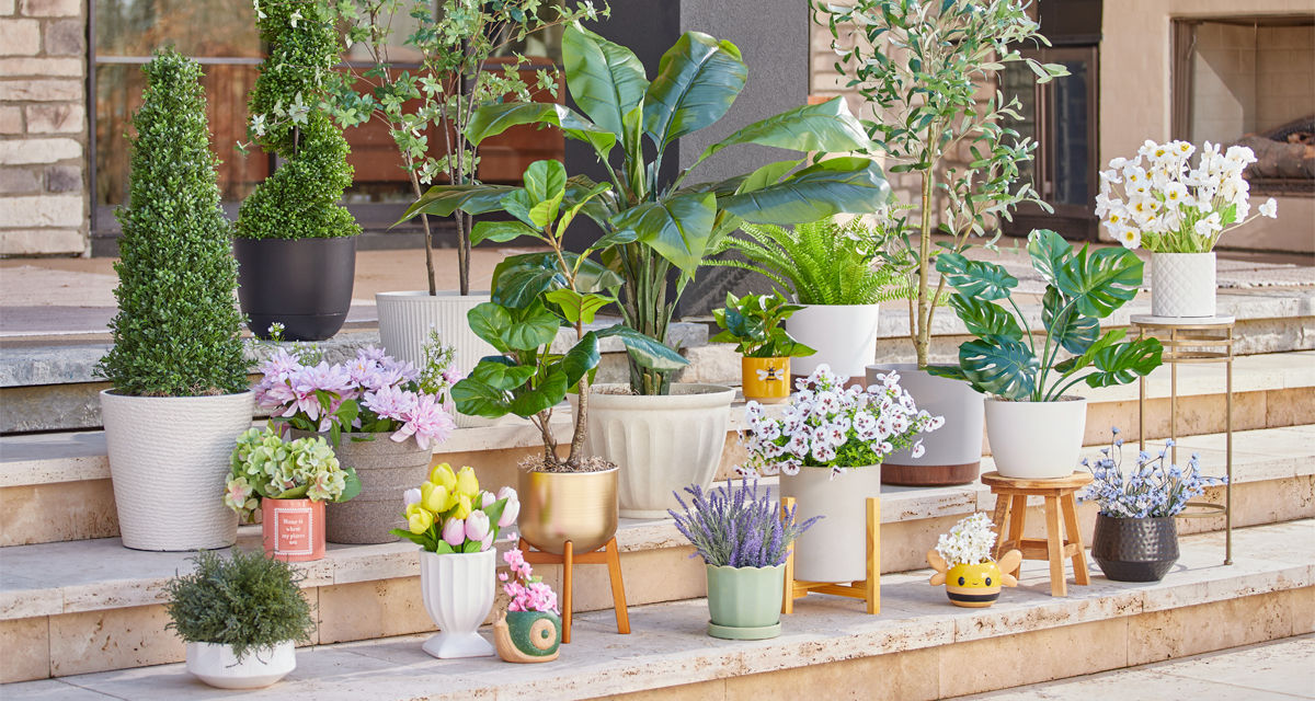 Various colors and designs of pOpshelf outdoor planters, flower pots, and plant stands filled with greenery and flowers on a patio.