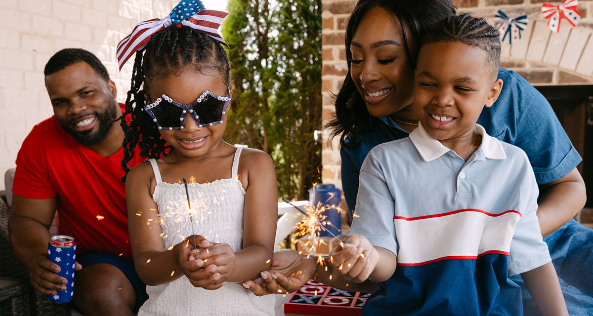 Family enjoying a backyard BBQ with patriotic decor, party supplies, and apparel.