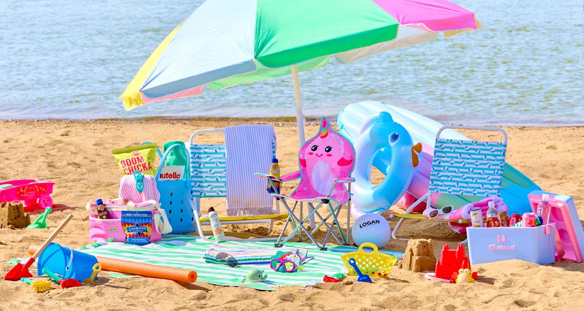 Beach scene with folding beach chairs, beach umbrella, beach towels, insulated coolers, snacks & sand toys.