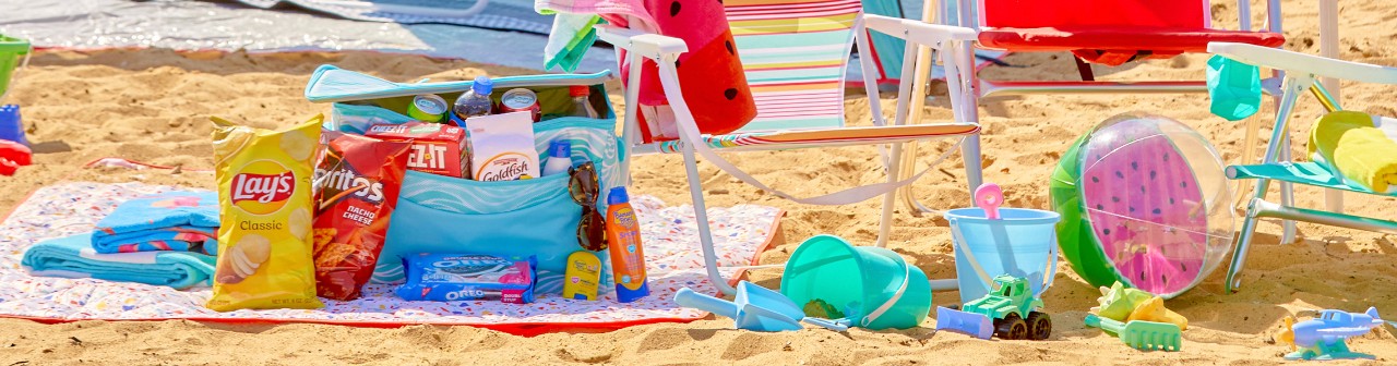 Blue Wave soft-side insulated cooler with drink and snacks on the beach with beach chairs, umbrellas, beach towels & more.