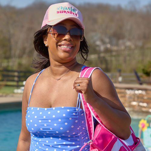 Woman in vacay vibes hat with a pink striped tote from popshelf.