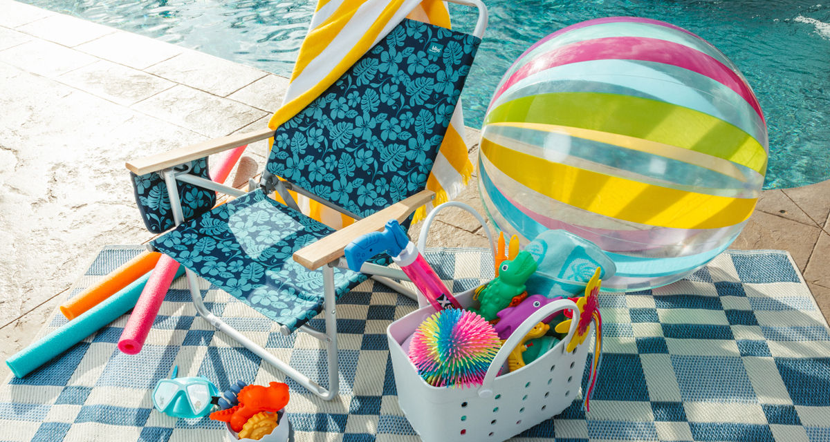 Blue folding beach chair by pool with beach towels, beach bag, pool toys & more