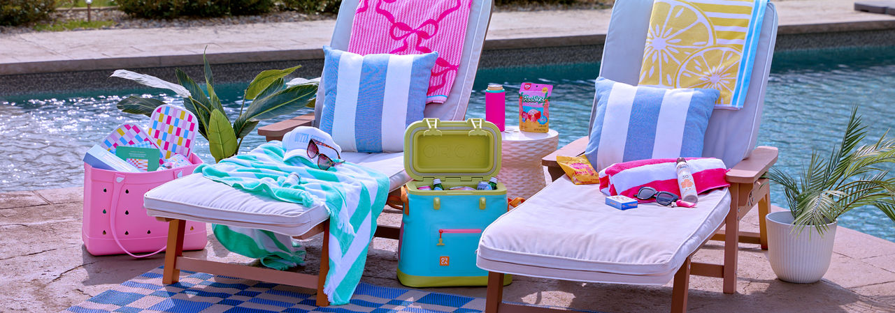 Yellow & green folding beach chairs poolside with floats, sand & water toys, beach towels, cooler with drinks & more.
