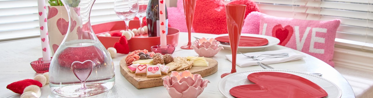 Romantic Valentine's Dinner for two with a heart charcuterie baoard, red heart-shaped plates and champagne glasses, heart glass decanter, rose petal candleholders & more.
