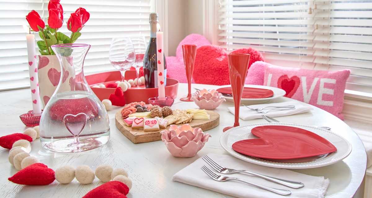 Romantic Valentine's Dinner for two with a heart charcuterie baoard, red heart-shaped plates and champagne glasses, heart glass decanter, rose petal candleholders & more.