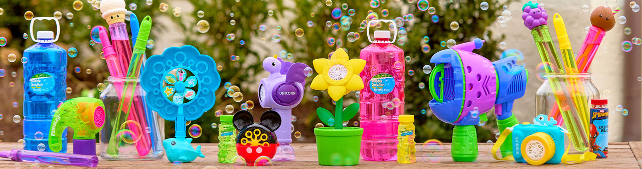 Outdoor table with bubbles, bubble blowers, bubble wands, and bubble machines in various colors and designs.