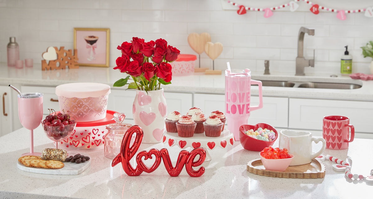Kitchen island with Valentine's cake stand, mugs, travel cup, flowers, candy  & Valentine's Day kitchen linens.